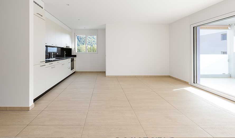 MTS Empty room with white walls, travertine floor and white kitchen and black marble